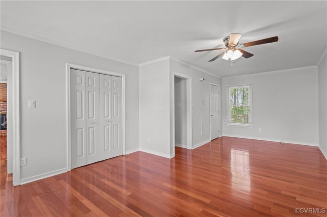 Unfurnished bedroom featuring wood finished floors, crown molding, baseboards, and ceiling fan | Image 5