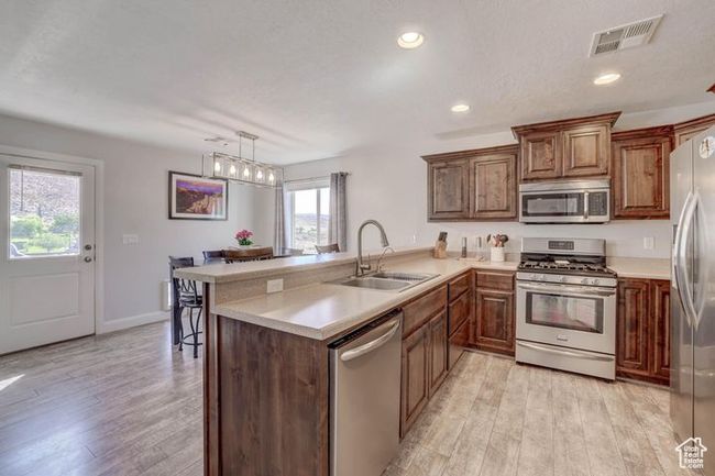 Kitchen with light wood finished floors, a peninsula, a sink, visible vents, and appliances with stainless steel finishes | Image 6