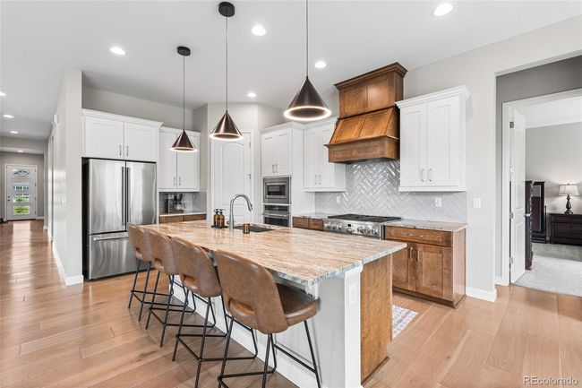 Chef's dream kitchen with upgraded pendant lighting, GE Cafe appliances (6-burner gas range, wall oven/airfryer, French door refrigerator) custom range hood and herringbone tile backsplash. Large granite island soft-close maple cabinets will roll-out drawers and large pantry. | Image 14