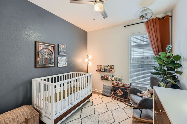 Bedroom featuring a crib, a textured wall, and ceiling fan | Image 22