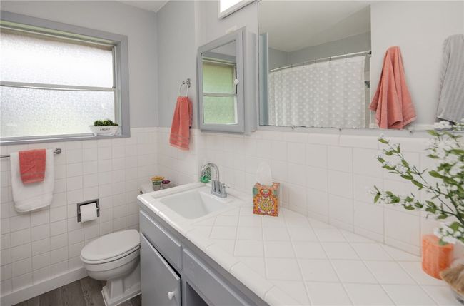 Full bathroom featuring vanity, toilet, a wainscoted wall, wood finished floors, and tile walls | Image 16