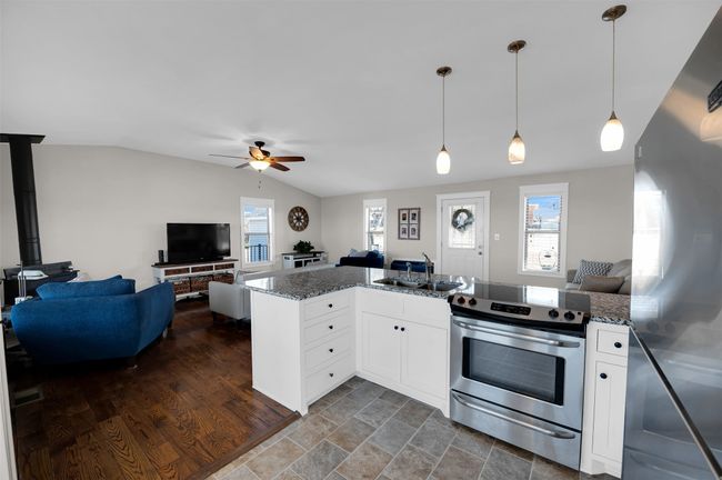 Kitchen with appliances with stainless steel finishes, open floor plan, a sink, lofted ceiling, and a ceiling fan | Image 7