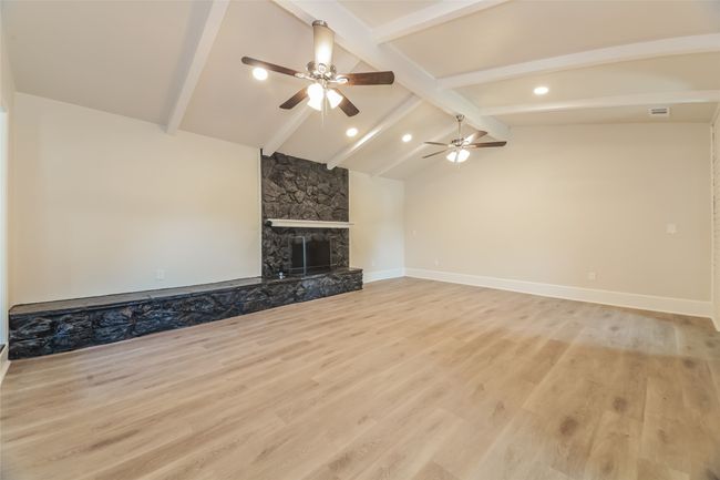 Unfurnished living room with wood finished floors, a fireplace, ceiling fan, and recessed lighting | Image 6