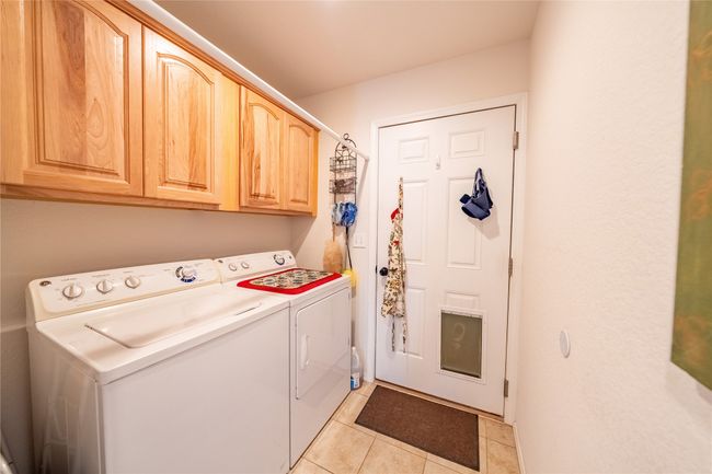 Clothes washing area with light tile patterned floors, cabinet space, and separate washer and dryer | Image 17