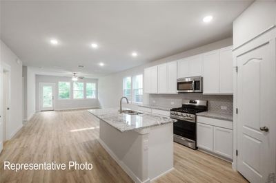 Kitchen featuring stainless steel appliances, an island with sink, light hardwood / wood-style floors, and white cabinets | Image 2