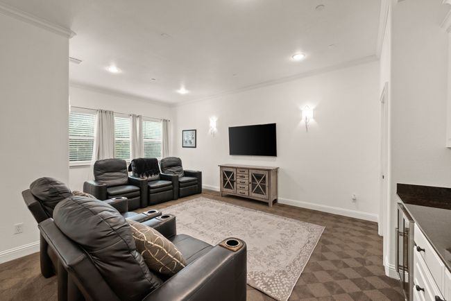 This upstairs versatile living area can be used as a game or media room, and includes ornamental molding, patterned carpet, recessed lighting, and a dry bar with beverage fridge. | Image 24
