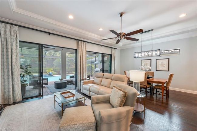 Living room featuring a raised ceiling, ornamental molding, a ceiling fan, wood finished floors, and recessed lighting | Image 11