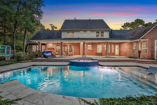 The back elevation of the home is truly impressive, showcasing an extended covered patio that seamlessly blends indoor and outdoor living. Just beyond, an expansive travertine deck surrounds the oversized, heated pool and spa, offering ample space for entertaining, dining, and lounging. | Image 42