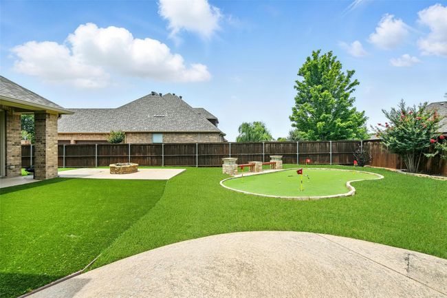 Fenced backyard featuring a putting area, a fire pit, and a patio | Image 9