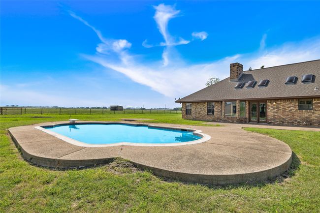 View of swimming pool with a diving board and a patio area | Image 20