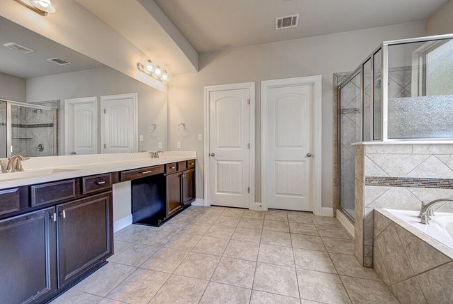 Full bath featuring double vanity, a garden tub, a stall shower, and tile patterned flooring | Image 16