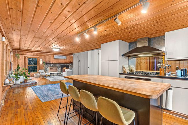 Kitchen with freestanding refrigerator, wall chimney exhaust hood, butcher block countertops, visible vents, and oven | Image 16