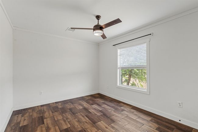 Empty room with ornamental molding, dark wood-style flooring, and ceiling fan | Image 20