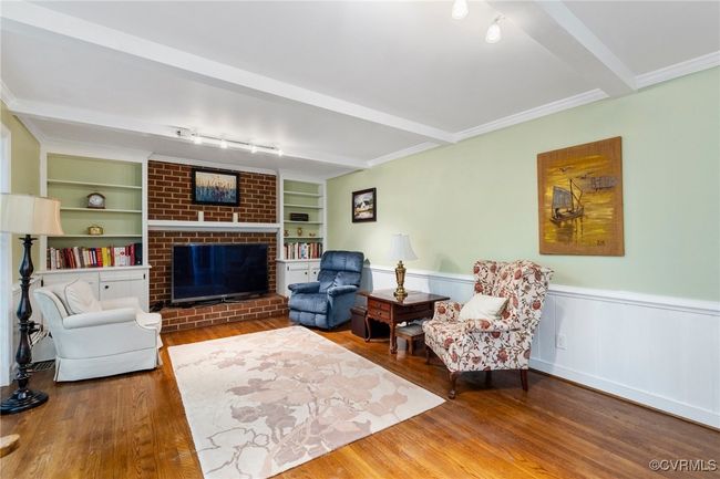 Living room with a fireplace, wood finished floors, wainscoting, and beam ceiling | Image 23