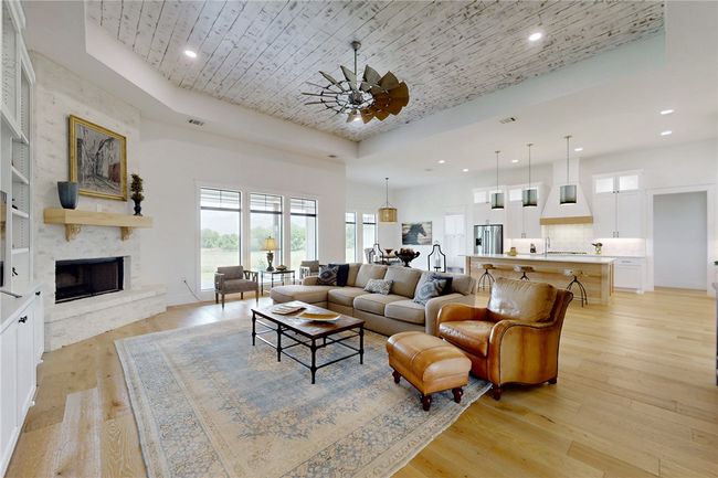 Living room featuring a raised ceiling, recessed lighting, light wood finished floors, a fireplace, and wooden ceiling | Image 6