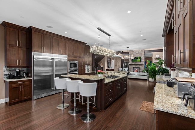 Kitchen featuring a kitchen bar, dark brown cabinets, a kitchen island, open floor plan, and built in appliances | Image 11