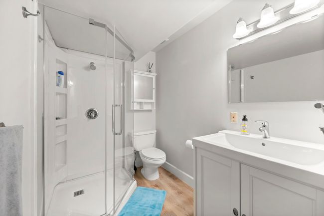 Bathroom featuring vanity, baseboards, toilet, a shower stall, and wood finished floors | Image 30