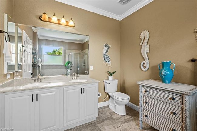 Bathroom with ornamental molding, a shower stall, toilet, double vanity, and baseboards | Image 27