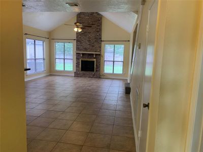 Cozy living room has tile floor, gas fireplace and lots of windows. | Image 3