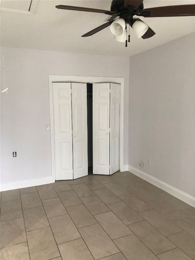 Unfurnished bedroom with light tile patterned floors, a closet, and ceiling fan | Image 11