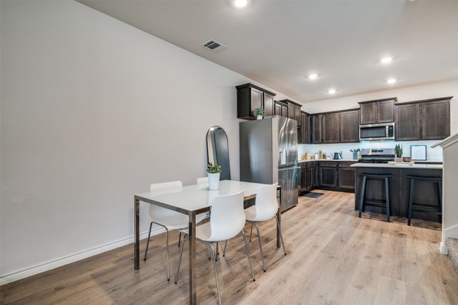 Kitchen featuring appliances with stainless steel finishes, dark brown cabinets, light wood-type flooring, light countertops, and recessed lighting | Image 9