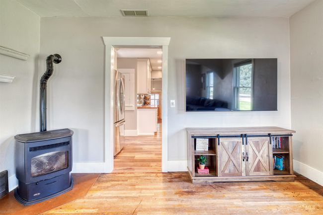 Living area featuring a wood stove and wood finished floors | Image 15