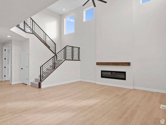 Unfurnished living room featuring recessed lighting, baseboards, stairs, light wood-style floors, and a glass covered fireplace | Image 8