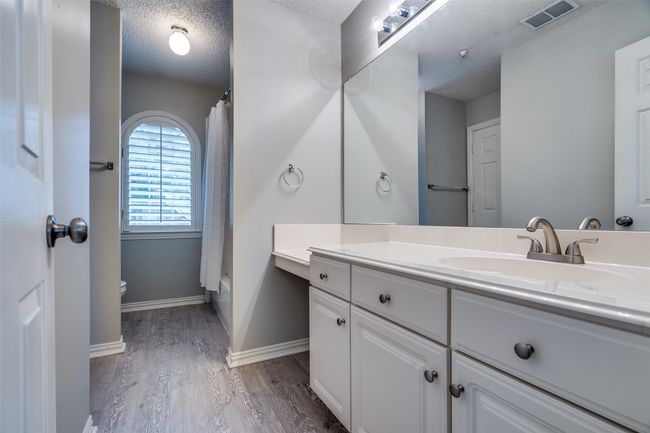 Full bath featuring a textured ceiling, vanity, wood finished floors, toilet, and baseboards | Image 19