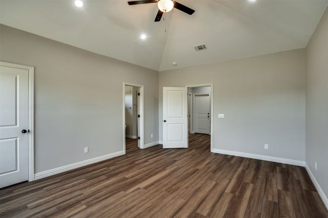 Unfurnished bedroom with baseboards, visible vents, high vaulted ceiling, and dark wood-style floors | Image 13