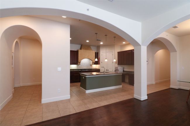 Kitchen featuring recessed lighting, dark countertops, a center island with sink, light wood finished floors, and a sink | Image 6