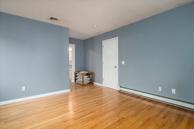 Spare room with a baseboard heating unit, light wood-type flooring, and a smoke detector | Image 17