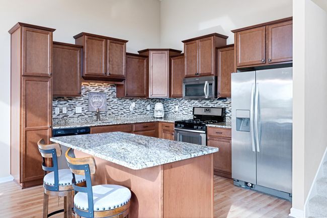 Spacious kitchen with large island, tons of cabinets and storage, stainless steel appliances, tile backsplash and granite counters. | Image 5