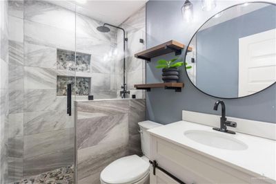 Bathroom featuring vanity, a shower with shower door, and toilet | Image 2