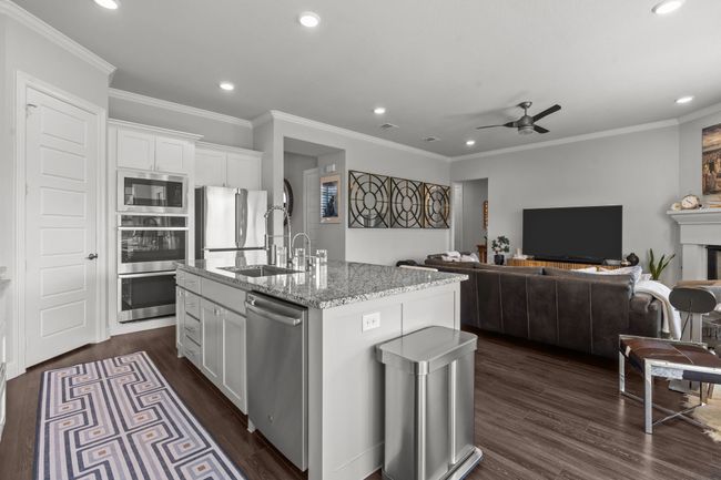 Kitchen with appliances with stainless steel finishes, recessed lighting, ceiling fan, light stone countertops, and white cabinetry | Image 6