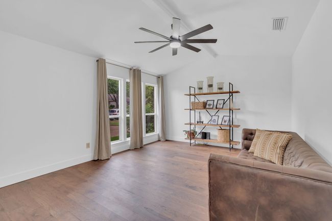 Living room featuring ceiling fan, visible vents, wood finished floors, baseboards, and vaulted ceiling with beams | Image 6