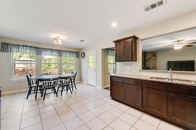 Kitchen with light tile patterned floors, a sink, visible vents, and dark brown cabinetry | Image 12