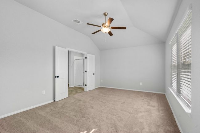 Unfurnished bedroom featuring carpet, multiple windows, vaulted ceiling, and visible vents | Image 15