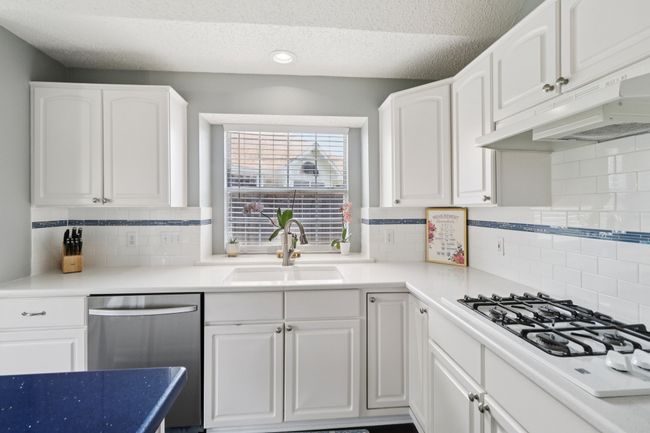 Kitchen with dishwasher, a sink, a textured ceiling, white cabinets, and recessed lighting | Image 14