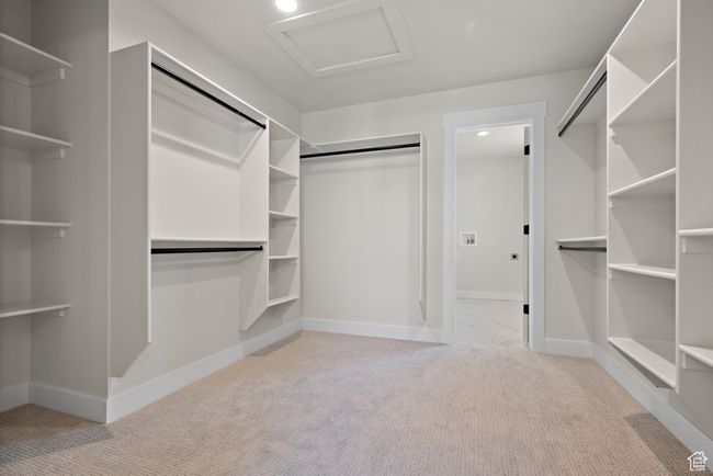 Spacious walk-in closet off the primary bedroom, direct access to laundry room, featuring carpet floors and attic access | Image 23