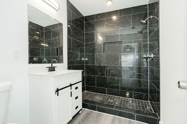 Full bath with a tile shower, wood finished floors, vanity, and toilet | Image 16