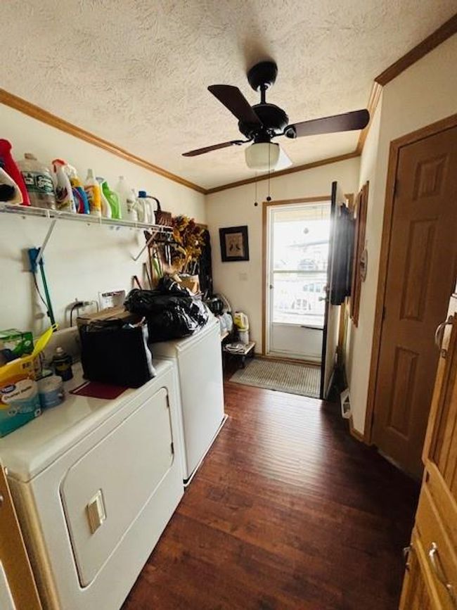 Laundry room featuring crown molding, independent washer and dryer, a ceiling fan, and dark wood-style floors | Image 21