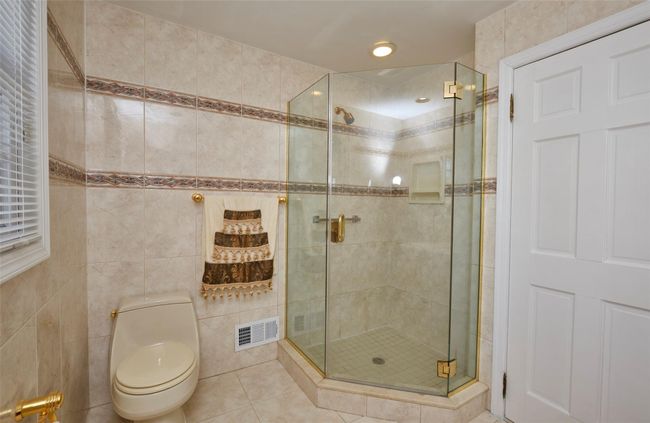 Bathroom featuring toilet, a stall shower, tile patterned flooring, and visible vents | Image 9