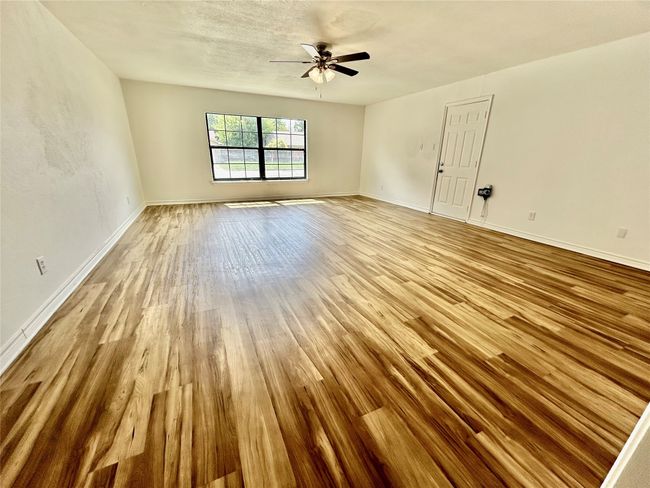 Empty room with wood finished floors, ceiling fan, and baseboards | Image 11