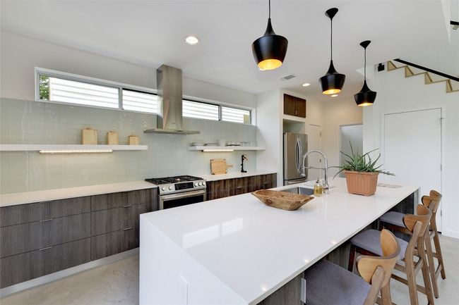 Kitchen featuring stainless steel appliances, an island with sink, visible vents, modern cabinets, and island range hood | Image 6