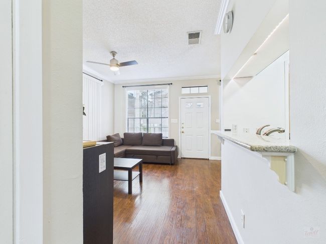 Living room with dark wood-style flooring, a textured ceiling, a ceiling fan, and crown molding | Image 16