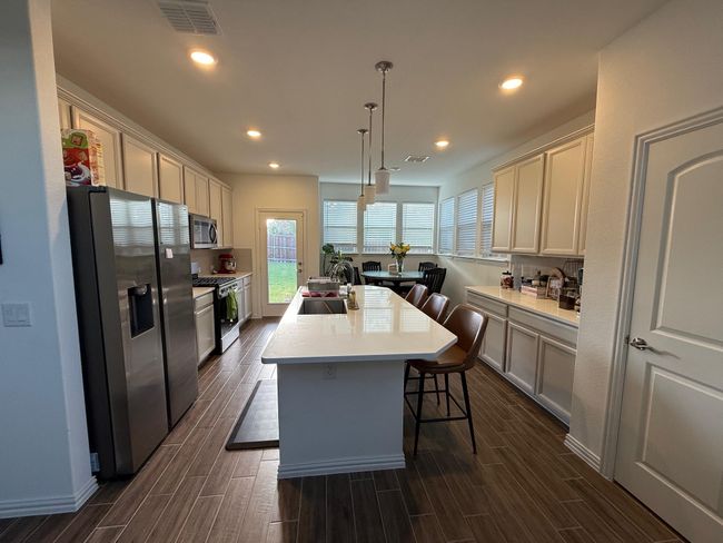 Kitchen with stainless steel appliances, a kitchen island with sink, dark wood finished floors, recessed lighting, and light countertops | Image 23