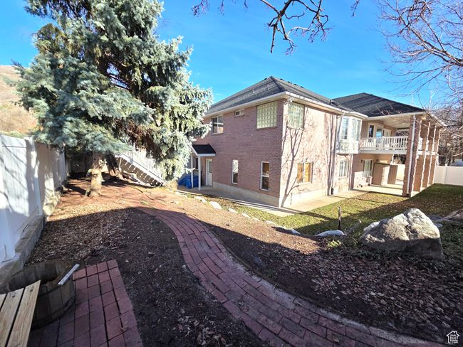 View of home's brick exterior featuring a covered deck, a fenced backyard, and covered patio area. | Image 37