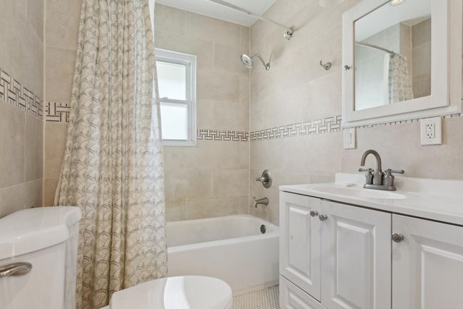 Full bathroom featuring tile walls, shower / tub combo with curtain, vanity, and toilet | Image 13