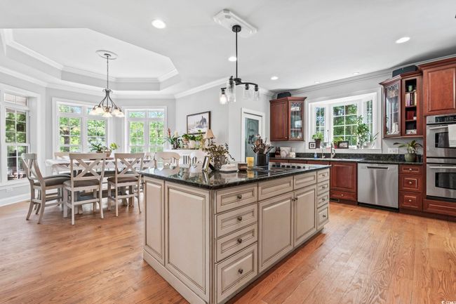 Kitchen with appliances with stainless steel finishes, light wood-style flooring, glass insert cabinets, pendant lighting, and crown molding | Image 10