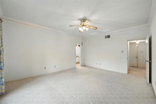 Empty room featuring crown molding, a ceiling fan, light colored carpet, and a textured ceiling | Image 21